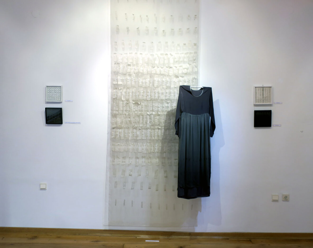 Fragment wystawy z białą tkaniną unikatową oraz zaprojektowaną przez artystkę suknią z jedwabiu naturalnego.