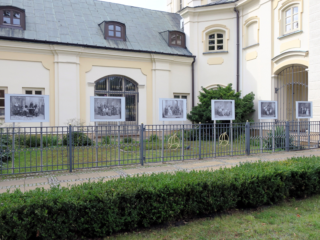 Fragment wystawy z widocznymi planszami zamocowanymi na ogrodzeniu wokół budynku ratusza.