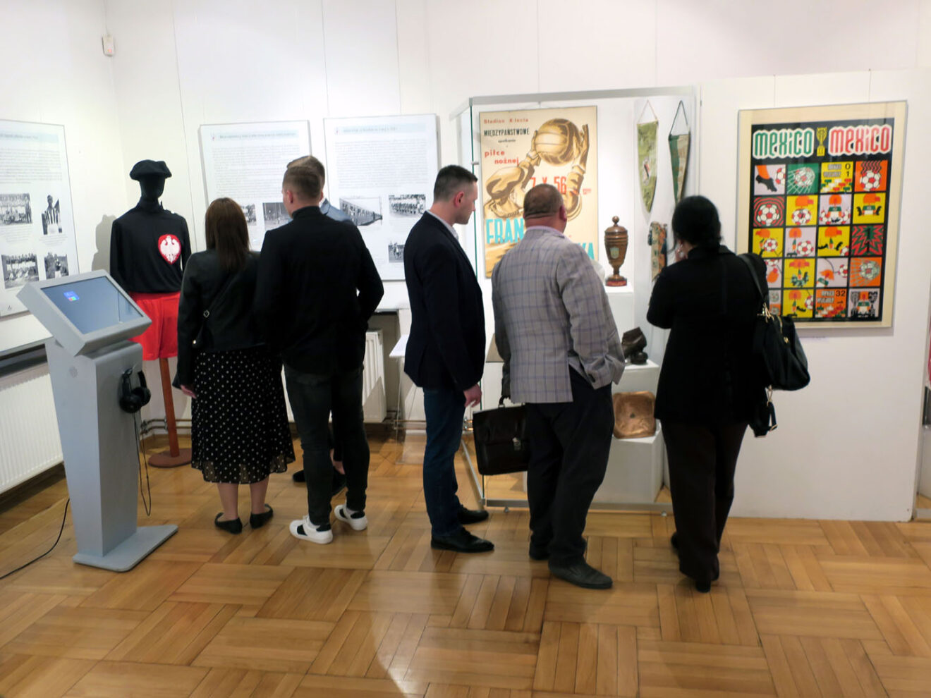 Grupa osób zwiedzających wystawę.