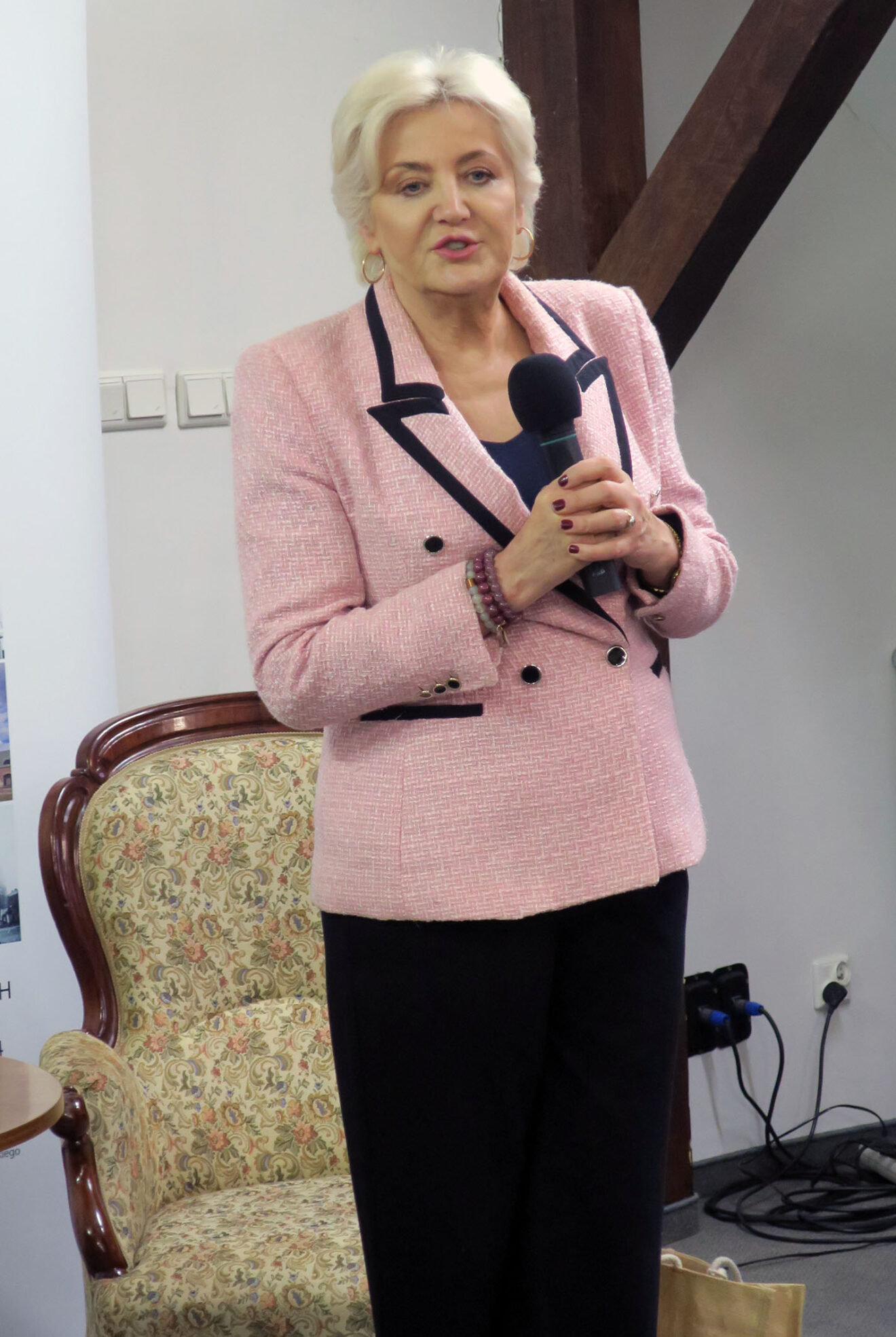 Fotografia stojącej kobiety trzymającej w rękach mikrofon.